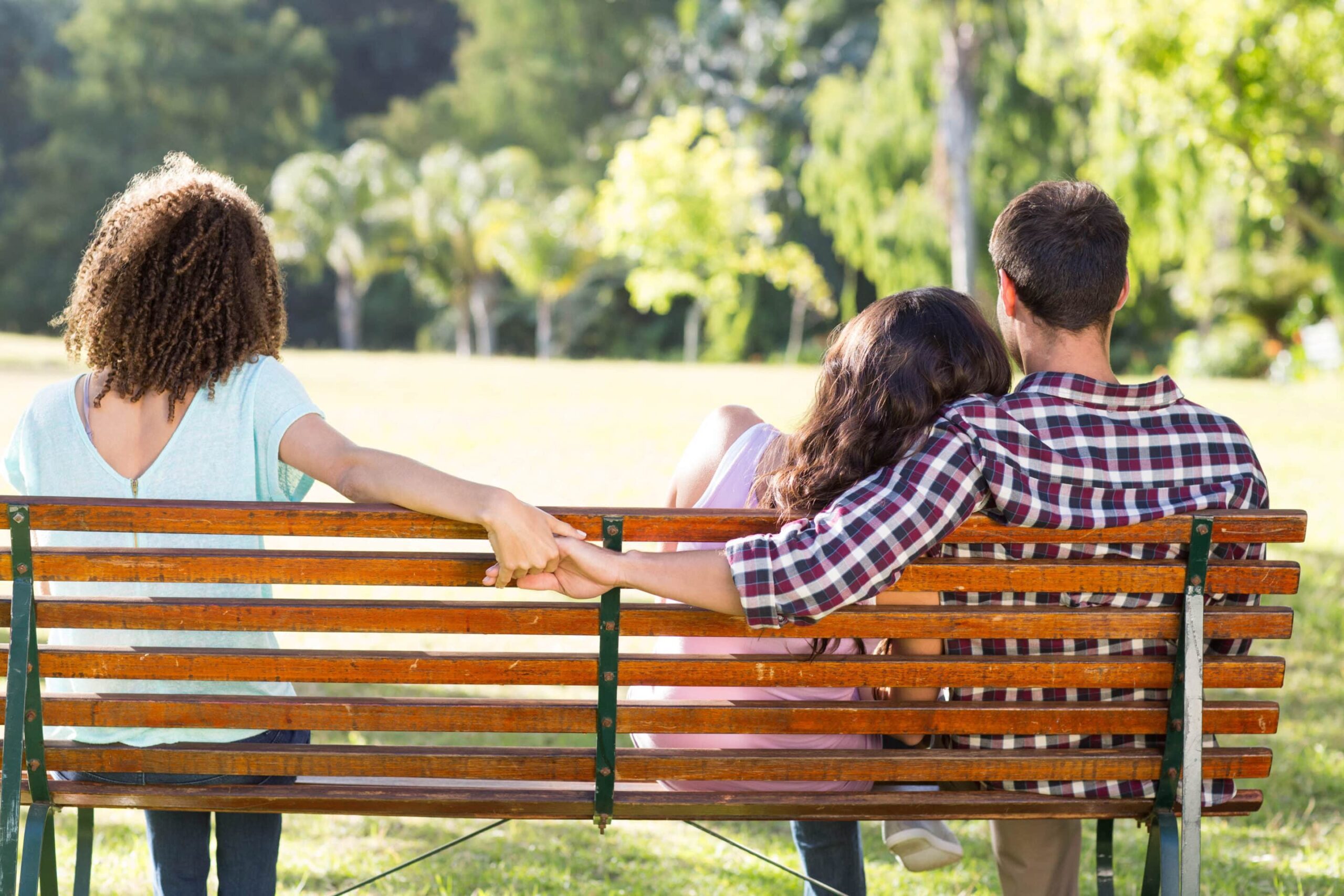 Lonely woman sitting with couple in park open or ethically non-monogamous marriage