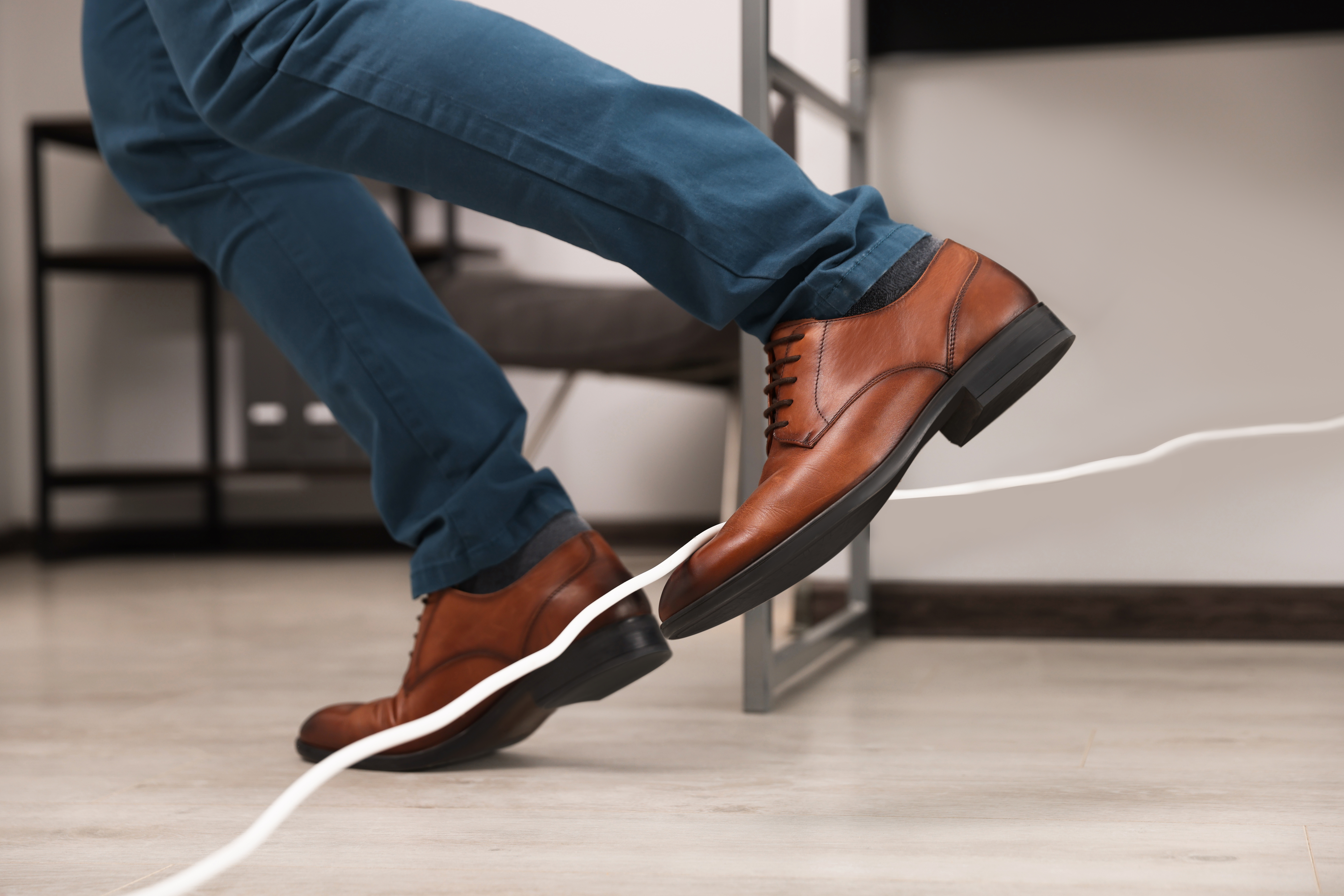 Man tripping over cord in office, closeup house